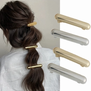 Detail of minimalist gold and silver metal bar hair clips showing high-polish finish