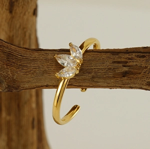 Bague réglable plaquée or avec trois zircons marquise posée sur une branche en bois
