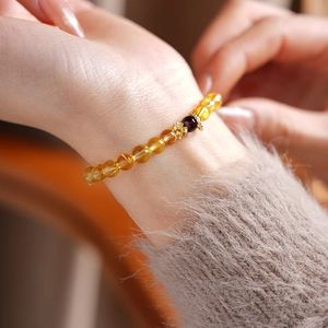 Macro view of citrine and garnet bead bracelet with a gold plum blossom charm on wrist
