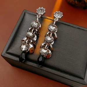 Macro shot of silver tassel earrings with clear crystals and a black teardrop pendant