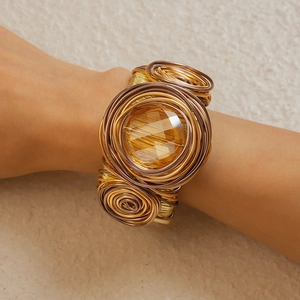 Detailed view of woven metal wire bracelet featuring a large amber faceted gemstone