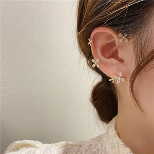 Elegant gold plated flower ear clips with pearls and zircon stones on a female model