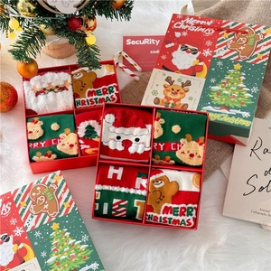 Close-up of Christmas combed cotton socks set in a red festive gift box with holiday props