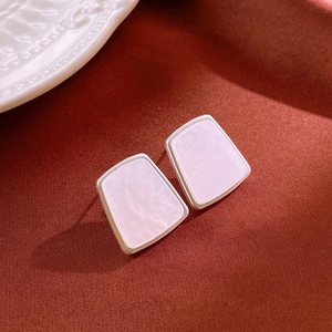 Gros plan de boucles d'oreilles trapèze dorées avec incrustation marbre sur tissu rouge