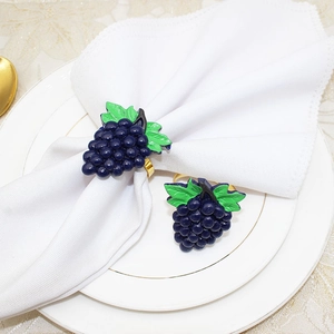 Detail of blue grape napkin rings with green leaves and gold metal ring for table decor