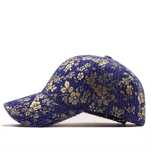 Detail of dark blue denim baseball cap featuring vintage gold foil floral embroidery