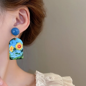 Detail of artistic sunflower drop earring worn by a model showcasing the unique arch shape