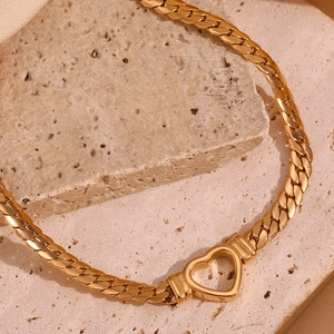 Macro shot of 18K gold plated heart pendant on a flat snake chain over stone