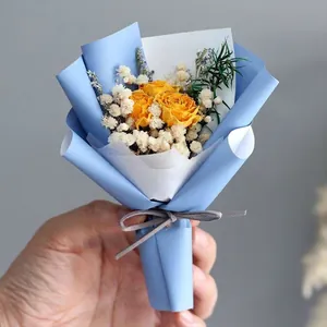 Close-up of mini bouquet with yellow dried roses, gypsophila and blue paper wrap