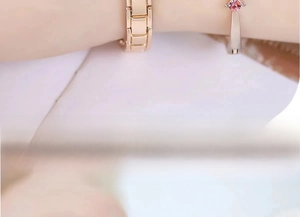 Close-up of elegant rose gold metal bracelets with pink gemstones on a female wrist