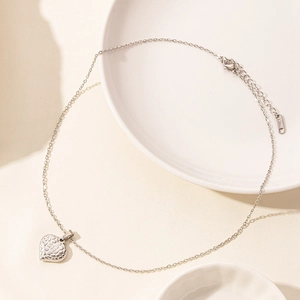 Macro shot of silver heart pendant with textured finish on stainless steel chain