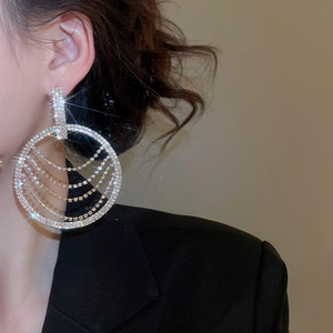 Gros plan de boucles d'oreilles à pompons argentés et cristaux sur un mannequin femme