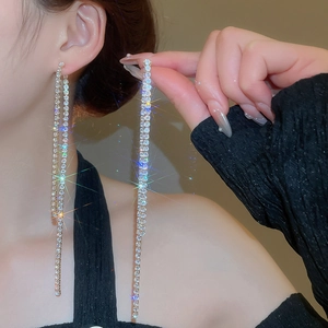 Detail view of long silver tassel earrings with sparkling zircons worn by a female model