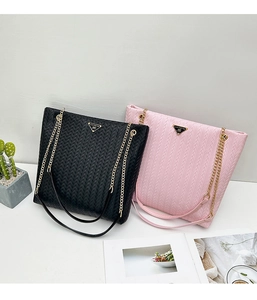 Detail of woven texture tote bags in black and pink with metal chain straps and plaque