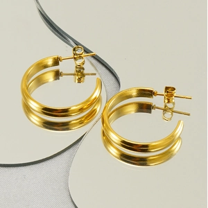 Macro shot of polished gold hoop earrings reflecting on a creative mirror surface