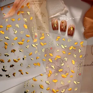 Detail view of golden ginkgo leaf nail stickers M-1247 on vintage paper background