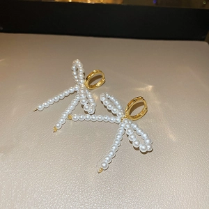 Gros plan détaillé de boucles d'oreilles nœud en perles avec anneaux dorés sur cuir doux