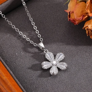 Macro d'un pendentif fleur argenté avec zircons dans une boîte grise avec fleurs séchées