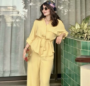 Detail of yellow loose-fit safari style linen shirt with drawstring waist and matching pants