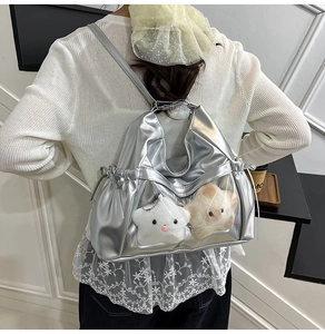 Detail of silver metallic backpack with clear window and plush star charms