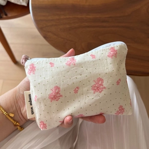 Close-up of floral cotton mini pouch with pink flowers and zipper closure held by hand