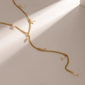 Macro detail of a gold 18K stainless steel chain necklace with natural white pearls