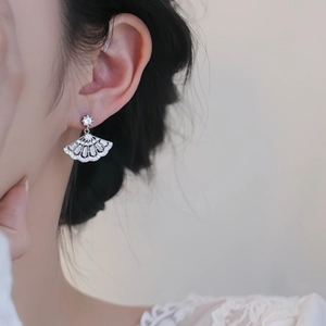 Detail of silver fan-shaped drop earrings with pavé zircons worn on model's ear