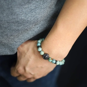 Macro view of blue tiger eye stone bracelet with lion head charm on male wrist