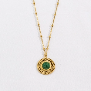 Close-up of gold satellite chain with green gemstone in a mandala circle pendant