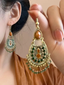 Détail de boucles d'oreilles bohèmes vintage avec perles orange et vertes en bronze vieilli