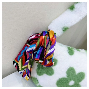 Detailed close-up of white plush handbag featuring green floral prints and silk scarf handle