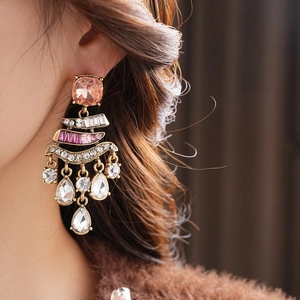 Macro detail of vintage gold earrings with pink gemstones and crystal waterdrop tassels