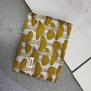 Detailed view of the mushroom jacquard fabric texture and brand label on a travel makeup bag