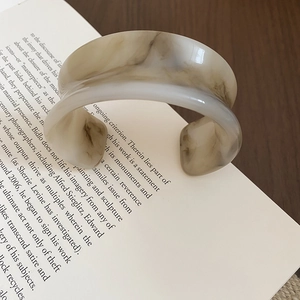Polished resin cuff bracelet with marble texture styled on an open vintage book