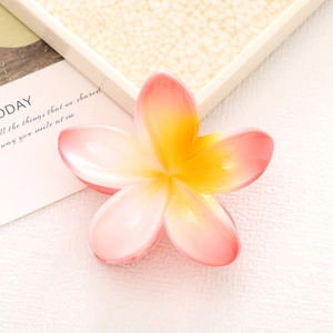 Detail of pink and yellow gradient frangipani hair claw clip on a white base