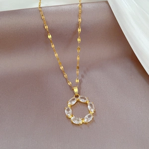 Macro shot of gold circle necklace with clear oval cubic zirconia on purple silk fabric