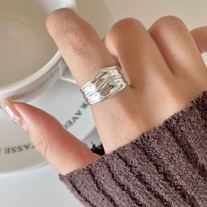 Detailed view of irregular wavy silver ring worn while holding a coffee cup