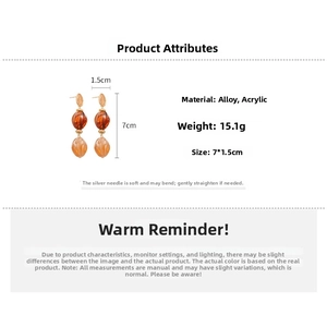 Detail view of acrylic dangle earrings with orange marble texture beads and alloy accents