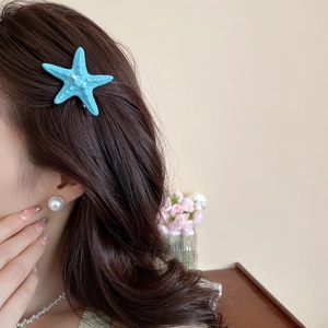 Detailed close-up of a blue starfish hair clip with realistic resin texture on wavy hair