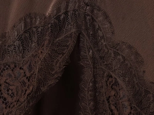 Vue macro de l'ourlet en dentelle de cils marron chocolat et texture lisse du tissu