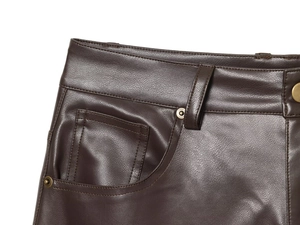 Dettaglio ravvicinato di pantaloni in pelle marrone scuro con rivetti in rame e cuciture