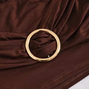 Macro shot of dark brown knit fabric texture and polished gold metal ring detail
