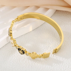 Detail of 18K gold stainless steel bangle with clover charms on champagne silk