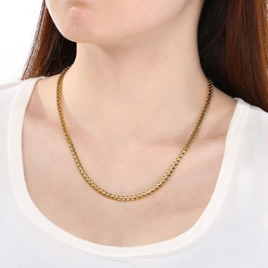 Polished gold snake chain necklace for men and women on a model neck with a white background