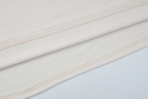 Macro detail of high-quality cream knit fabric with precise stitching and fine texture