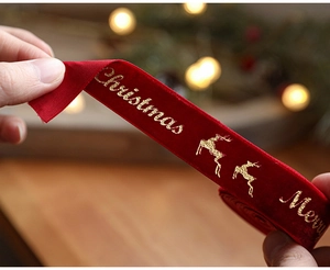 Close-up of red velvet Christmas ribbon with gold Merry Christmas print and reindeer