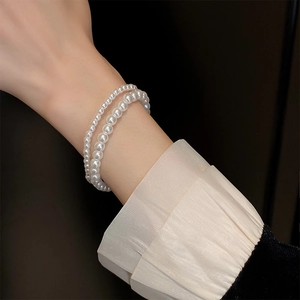 Detail of elegant double-layered pearl elastic bracelet on wrist with pleated cuff
