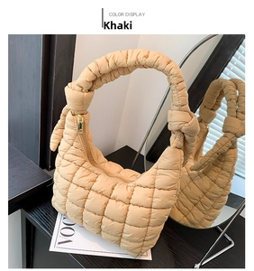 Detail of khaki quilted cloud bag featuring a decorative knotted handle and golden zipper