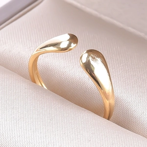 Macro shot of minimalist gold teardrop open ring on soft silk jewelry box lining