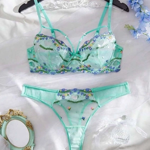 Detail of mint green mesh bra set with floral embroidery on white silk background